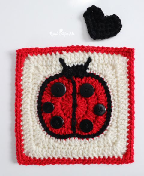 a crocheted square with a ladybug on it and a black heart