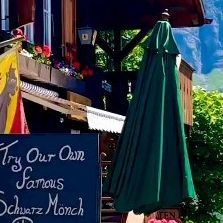 an outdoor cafe with umbrellas and flowers in the foreground on a sunny day