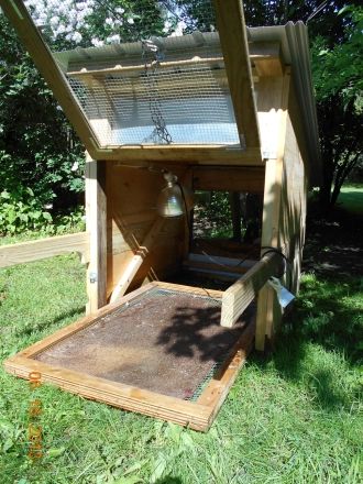 a chicken coop in the middle of some grass with an open door on it's side