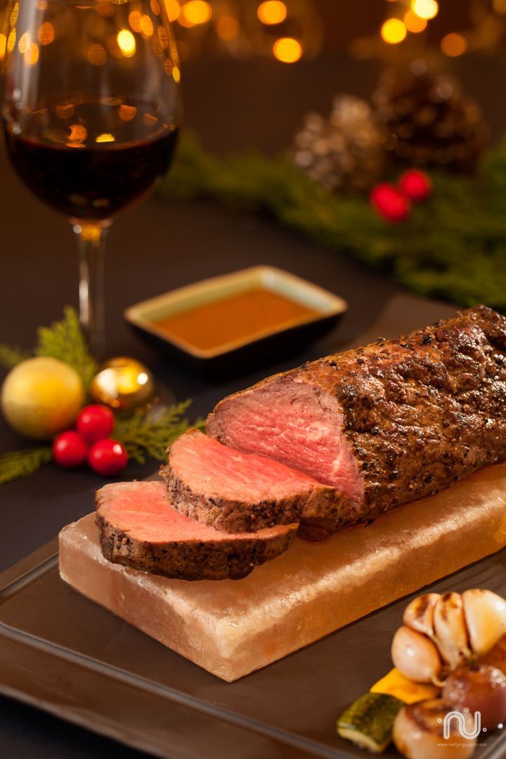 a piece of meat sitting on top of a wooden cutting board next to a glass of wine