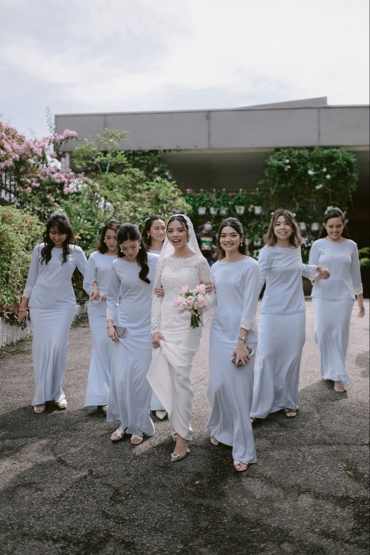 a group of women standing next to each other in long white dresses and holding bouquets