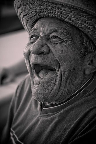 an old man wearing a hat and making a funny face with his mouth wide open