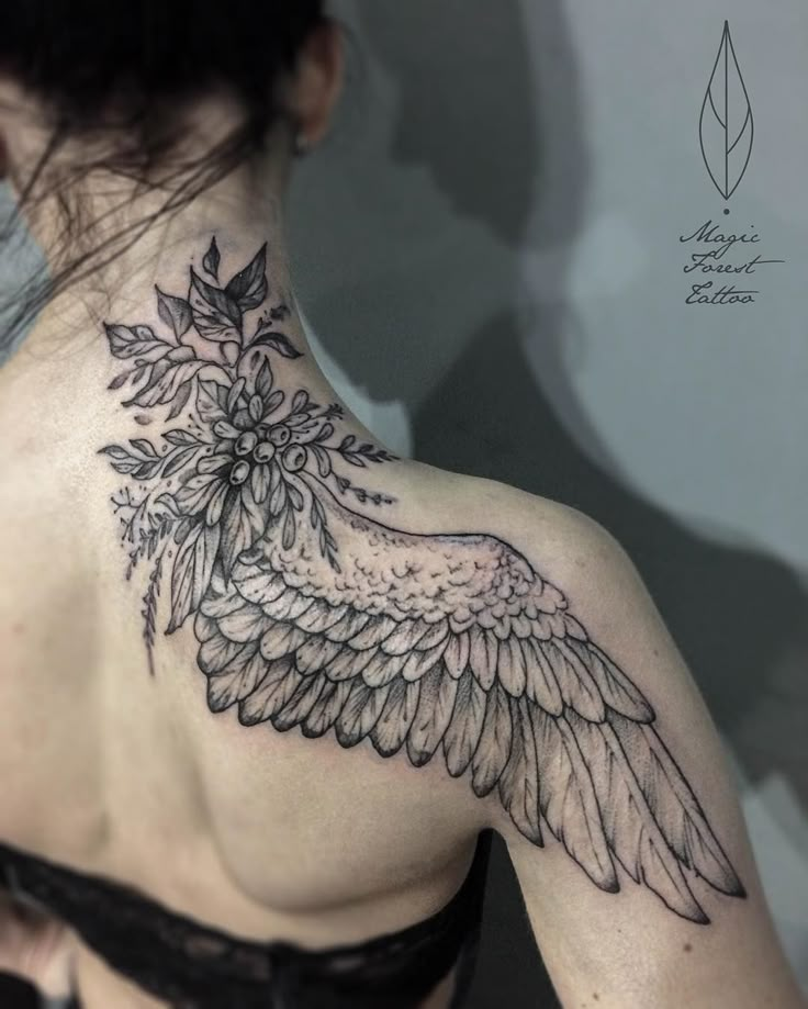 the back of a woman's shoulder with an angel wing tattoo on her upper arm