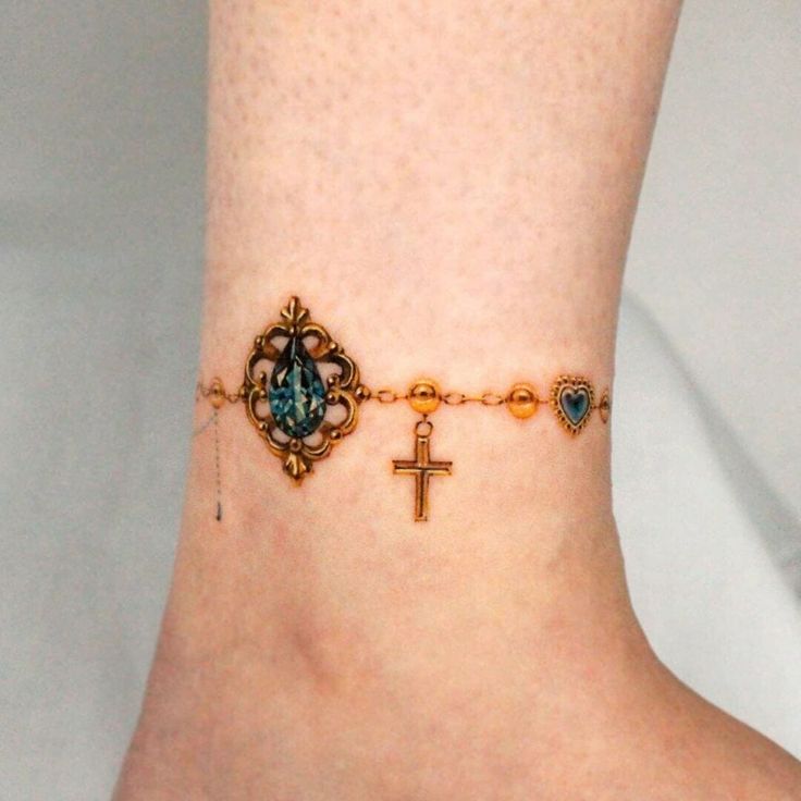 a woman's foot with a cross and blue stone bracelet on her left ankle