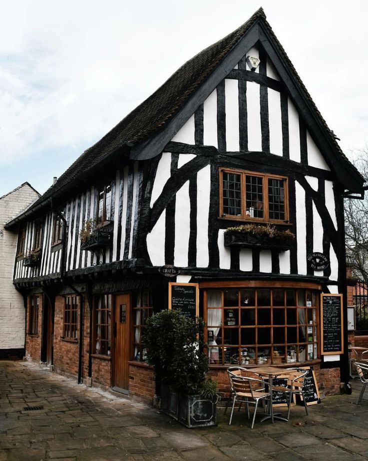 an old black and white building with tables outside