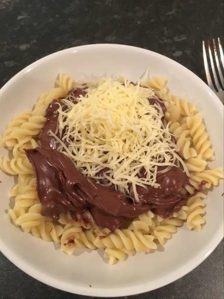 a white plate topped with pasta covered in sauce and cheese