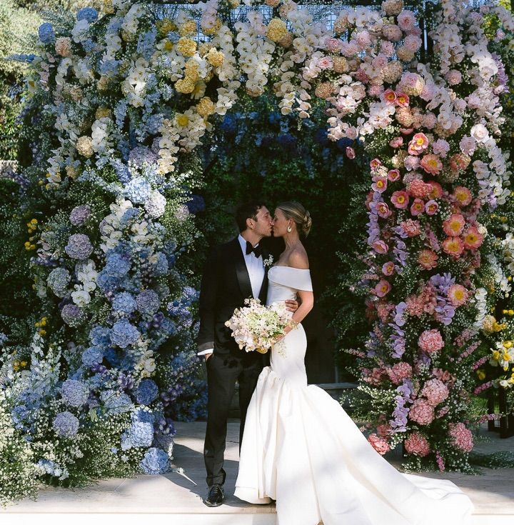 a bride and groom standing in front of a flower wall