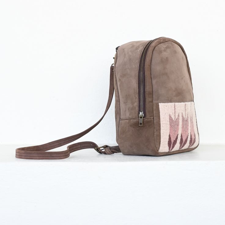 The lightweight mini backpack lets you carry your essentials in comfort and minimalist style with a low profile. Sophistication meets function in this lovely little backpack which perfectly fits your wallet, phone and even your favorite book. Traditional techniques and natural dyes are used to achieve these gorgeous hues of sand, pink and purple. Main compartment: 8" x 10" x 3" Front pocket: 7" x 4.5" Internal zippered pocket Straps: 31" - 35" Brown Standard Backpack With Mobile Phone Bag, Brown Backpack With Mobile Phone Bag, Beige Backpack With Phone Pocket For Daily Use, Beige Travel Backpack With Mobile Phone Bag, Leather Backpack With Mobile Phone Bag For Daily Use, Travel Backpack With Mobile Phone Bag, Everyday Backpack With Mobile Phone Bag, Beige Leather Backpack With Zipper Pocket, Beige Backpack With Cell Phone Pocket For Everyday Use