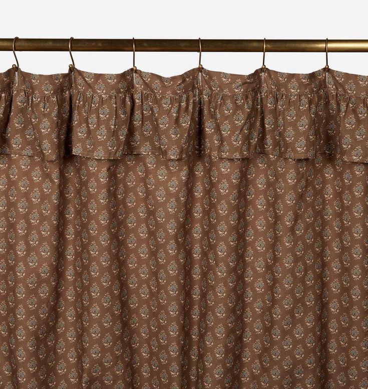 the curtain is hanging on a rod and has a brown flower pattern with white flowers