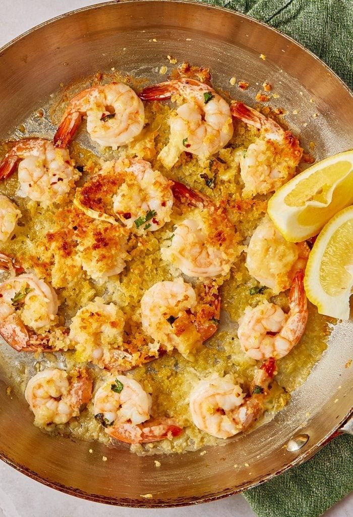 a pan filled with shrimp and lemon on top of a table