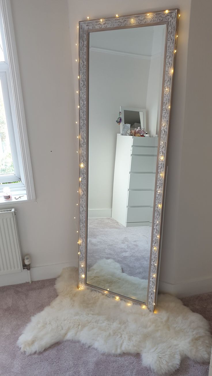 a mirror that is sitting on the floor with lights in front of it and a fur rug