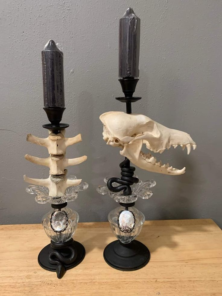 two candles are sitting next to each other on a table with a skull in the middle