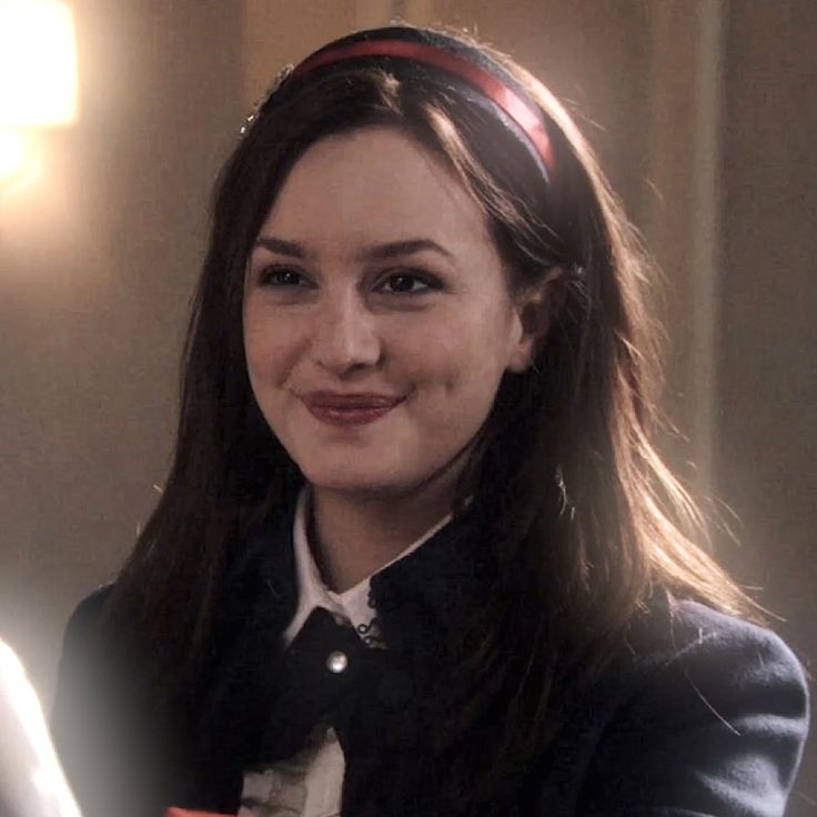 a woman with long brown hair wearing a black jacket and white shirt smiling at the camera