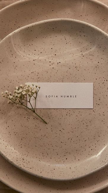 there is a small flower on top of a plate with a name tag attached to it