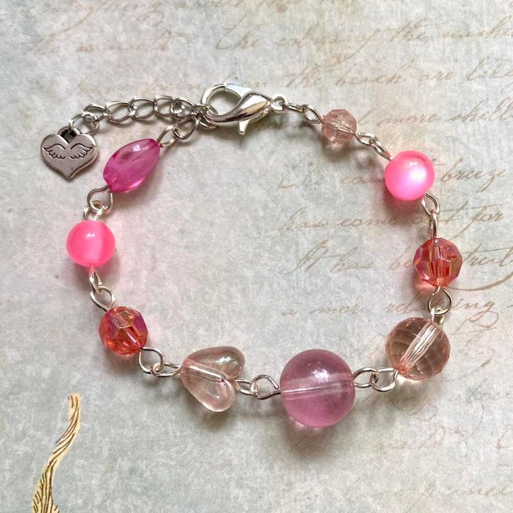 "🌸🌿 Pretty pink tone beaded bracelet! So cute with an assorted mix of beads~ bracelet measures at approx 7\" adjustable up to 8\" 🌸🌿 Handcrafted with love by me~" Pink Round Beads Charm Bracelet For Friendship, Pink Charm Bracelet With Round Beads For Friendship, Pink Bohemian Jewelry With Heart Beads, Bohemian Pink Jewelry With Heart Beads, Pink Jewelry With Colorful Beads For Valentine's Day, Bohemian Pink Heart Beads Jewelry, Pink Valentine's Day Jewelry With Colorful Beads, Valentine's Day Pink Jewelry With Colorful Beads, Pink Heart Beads Jewelry For Friendship