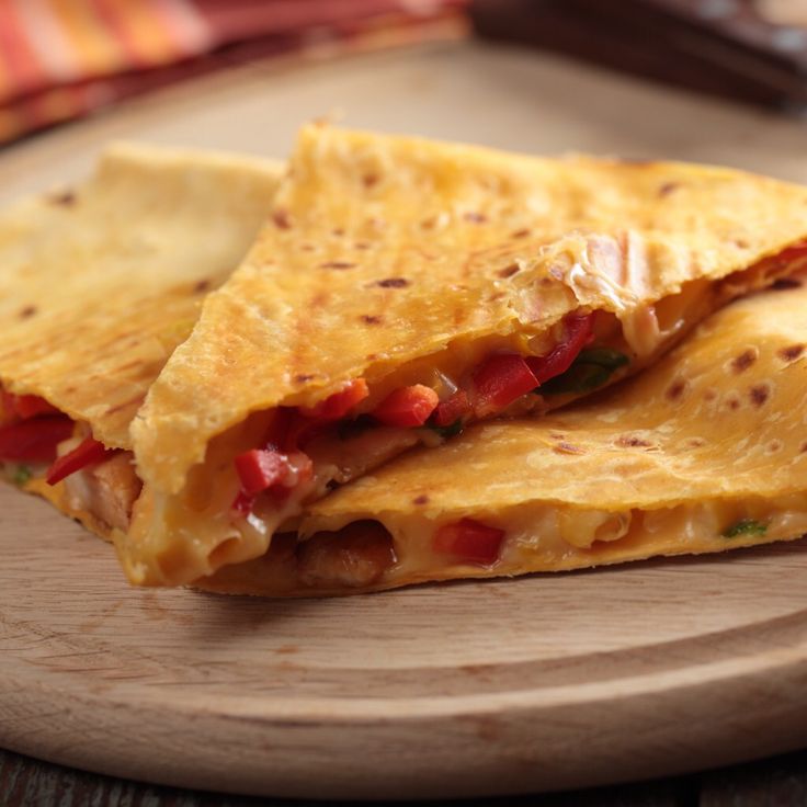 two quesadillas cut in half on a cutting board