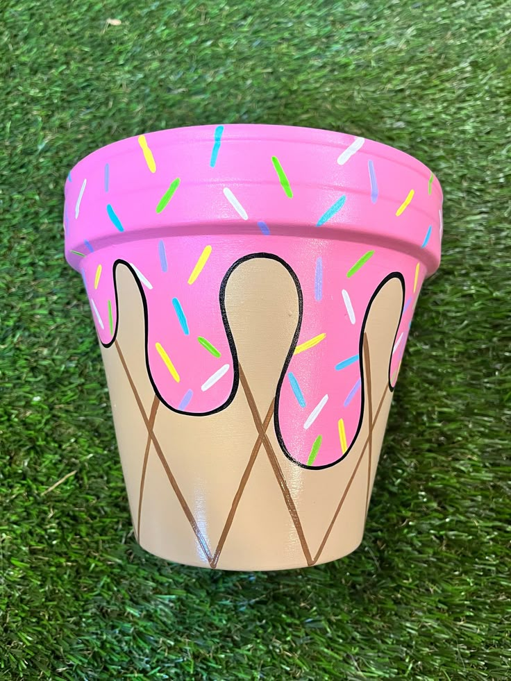 an ice cream cone with sprinkles painted on it sitting in the grass