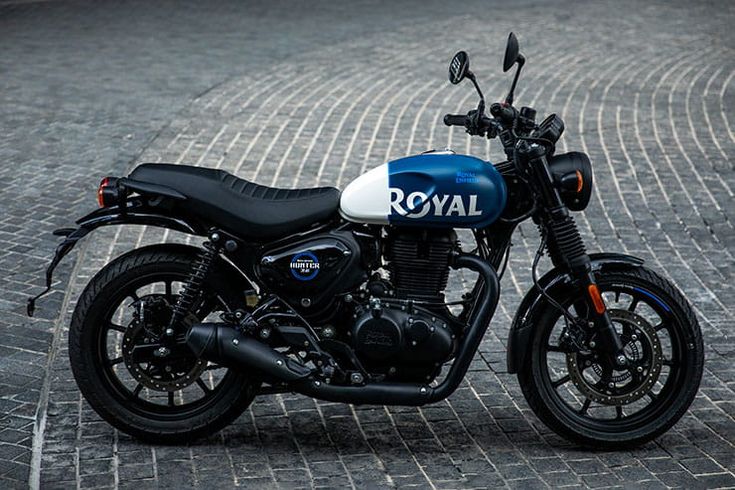 a blue and white royal motorcycle parked on a cobblestone street in front of a building