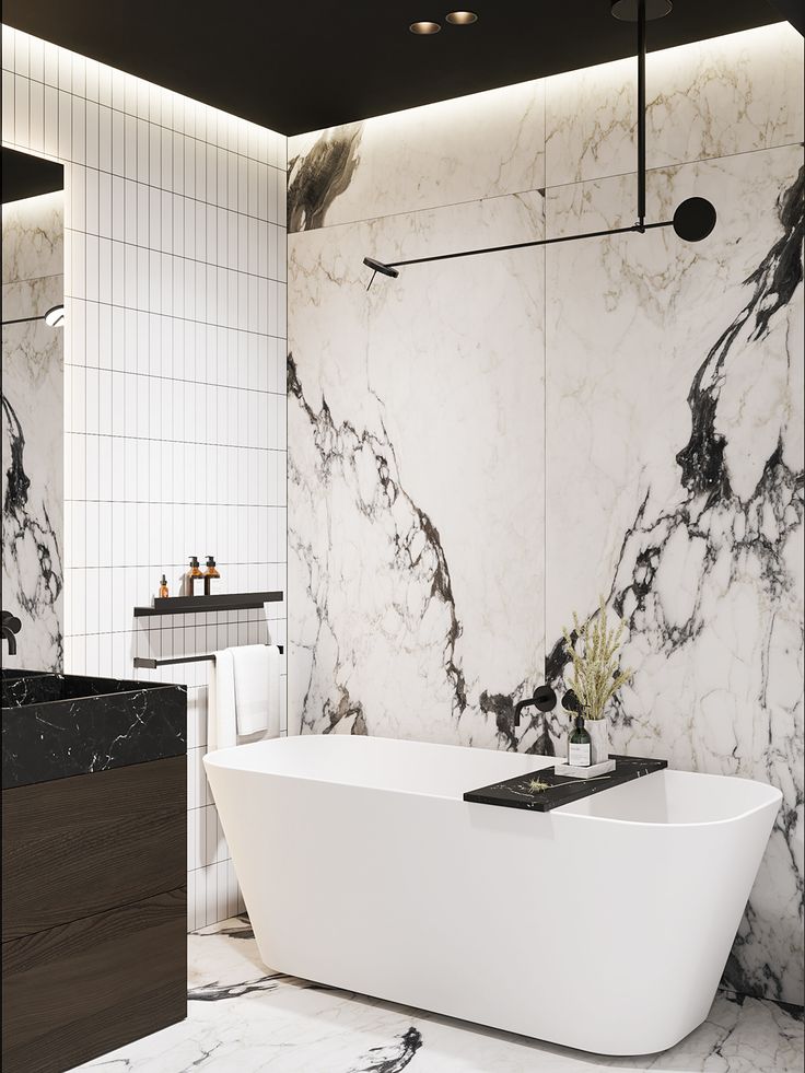 a white bath tub sitting in a bathroom next to a black and white tiled wall