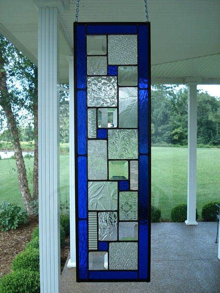 a stained glass window hanging from the side of a porch in front of a house