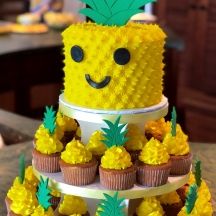 a three tiered cake with pineapples and cupcakes on the bottom