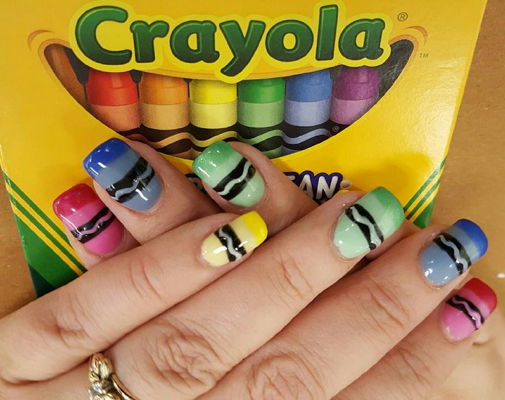 a woman's hand with colorful nail polish and crayola on it, next to a box of crayols