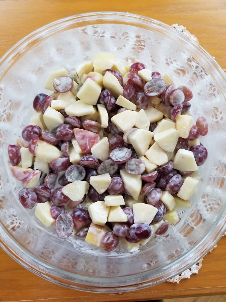 a glass bowl filled with grapes and cheese