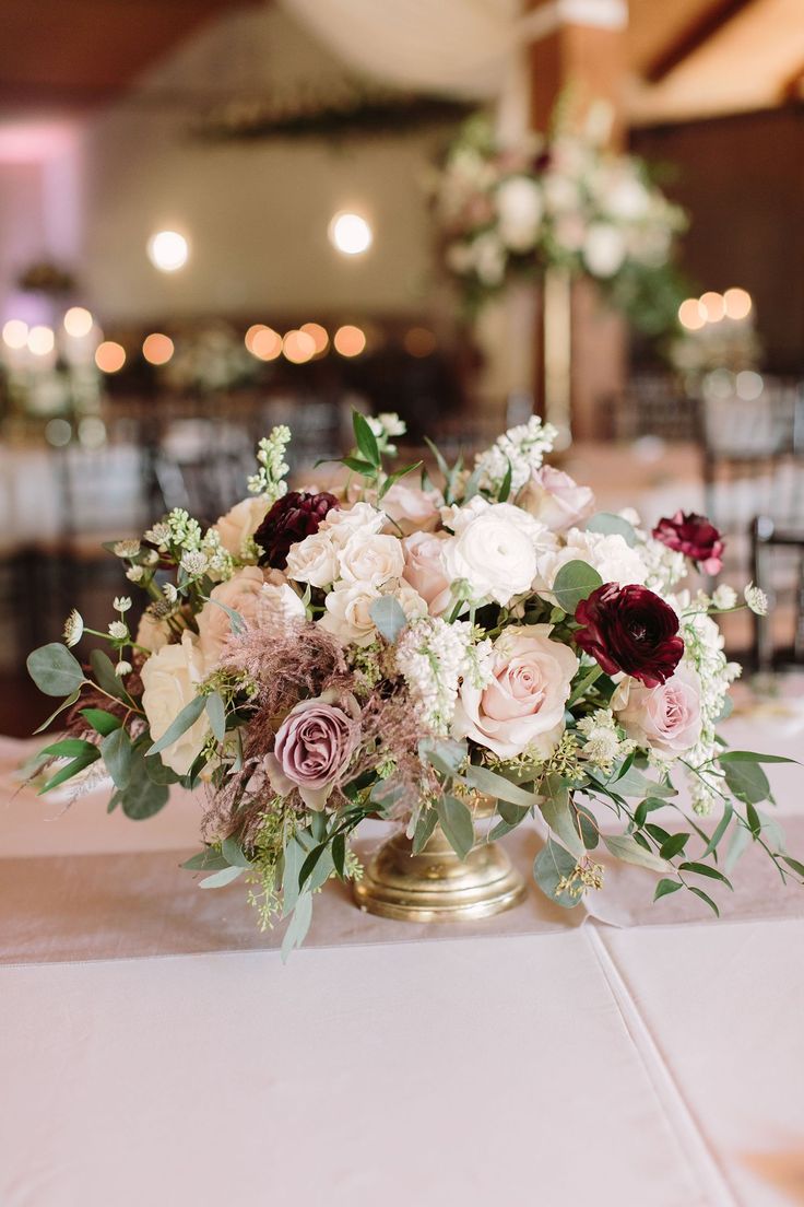 a vase filled with lots of flowers on top of a white table cloth covered table