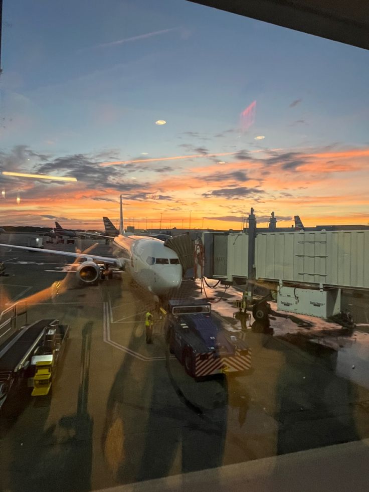 an airplane is parked on the tarmac at sunset