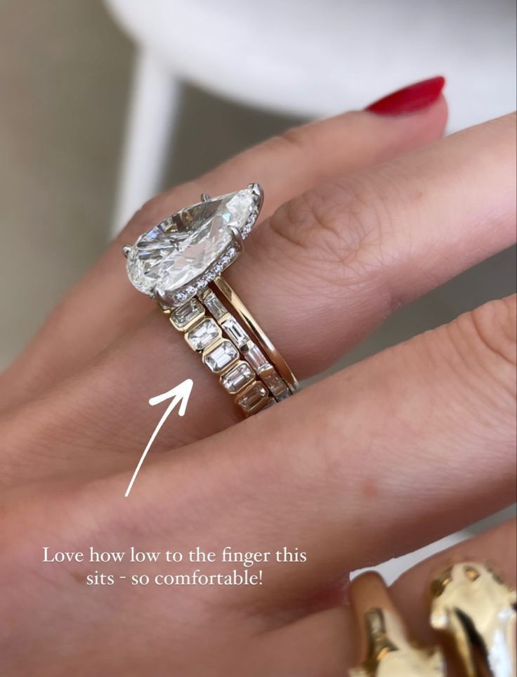 a woman's hand with two gold rings and an engagement ring on her finger