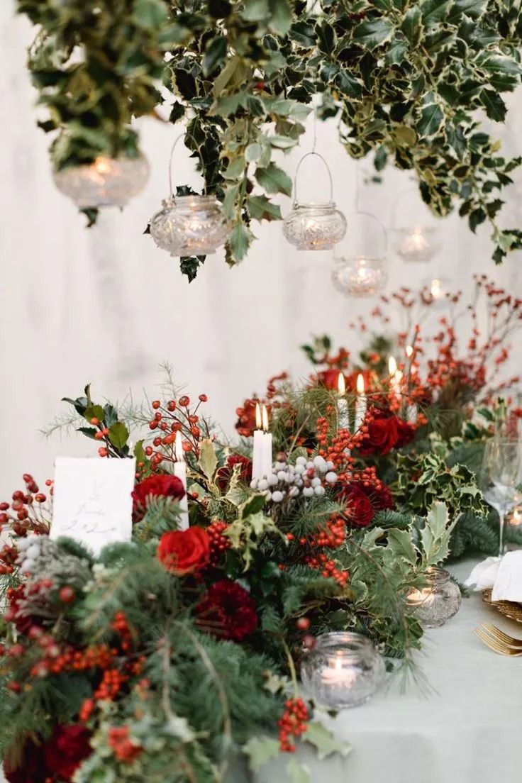 a table topped with lots of red flowers and greenery