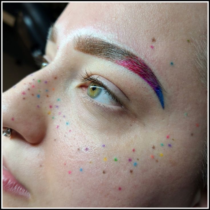 a woman's face with multicolored confetti on her cheek and eyebrows