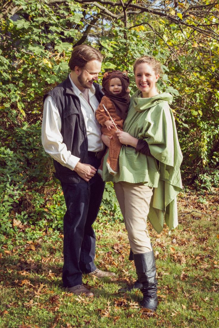 a man and woman are standing in the grass with a child on their lap,