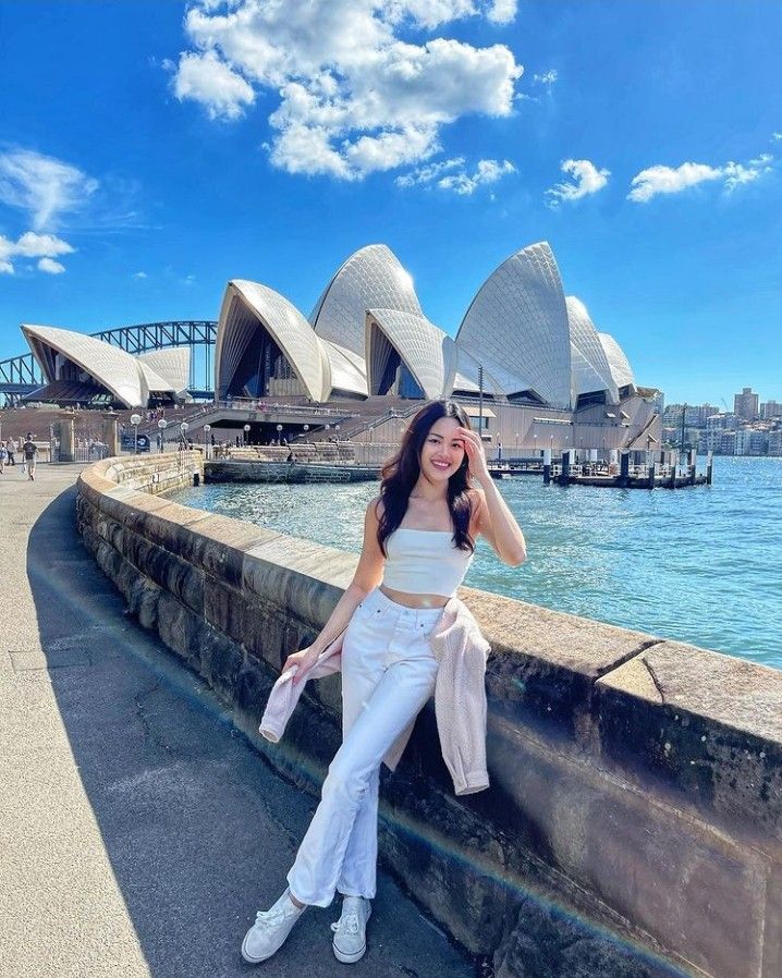 a woman posing for a photo in front of the sydney opera