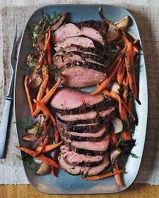 sliced pork with carrots and parsley on a platter next to a fork