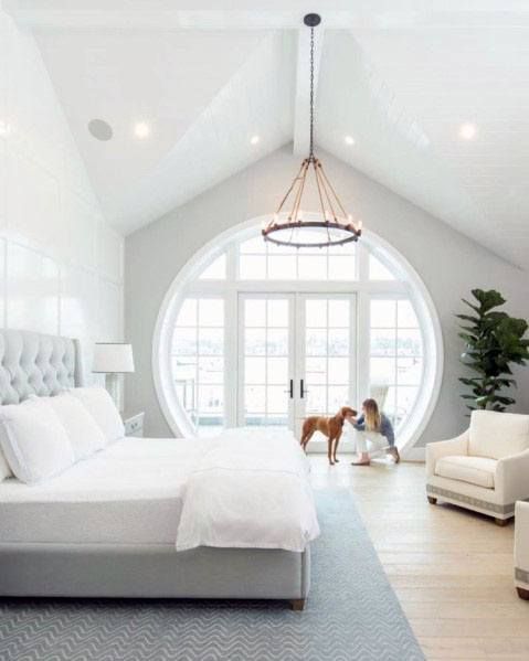 a bedroom with a large white bed in the center and a dog on the other side