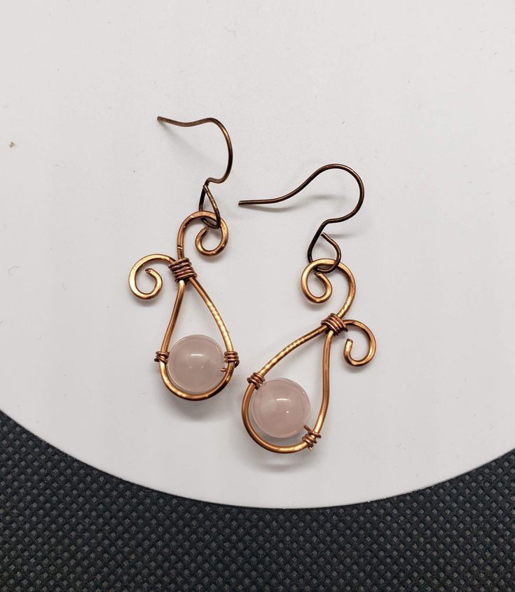 These earrings were made from copper wire and feature a genuine rose quartz stone bead in the center. The earring hooks are nickel free and copper colored to match. Adjustable Wire Wrapped Rose Gold Earrings, Adjustable Rose Gold Wire Wrapped Earrings, Rose Gold Wire Wrapped Copper Wire Earrings, Rose Gold Wire Wrapped Earrings In Copper, Rose Gold Wire Wrapped Earrings, Nickel Free Rose Gold Copper Wire Earrings, Nickel-free Rose Gold Copper Wire Earrings, Rose Quartz Earrings, Rose Quartz Stone