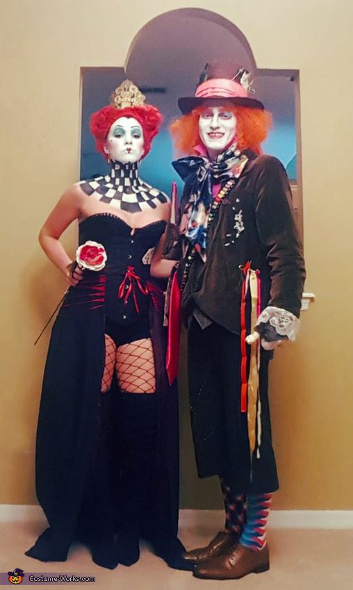 two clowns dressed in costumes standing next to each other near a poster on the wall