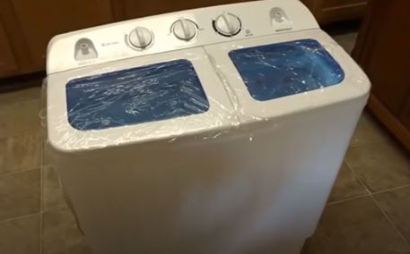 a white washer sitting on top of a kitchen floor