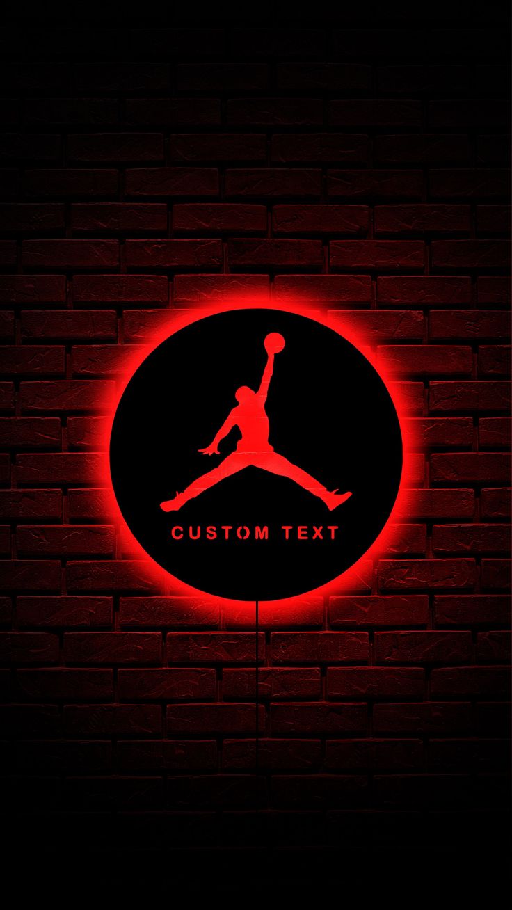 the air jordan logo is lit up on a brick wall with red light behind it