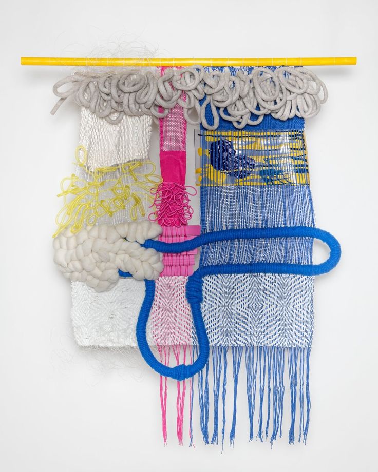 an art work made with yarn, thread and other materials on a white wall next to a yellow pencil