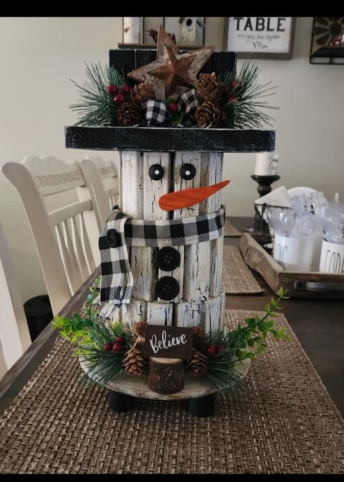 a snowman made out of wooden boards sitting on top of a dining room table