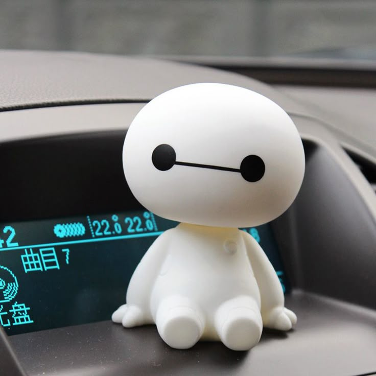 a small white toy sitting on top of a car dashboard