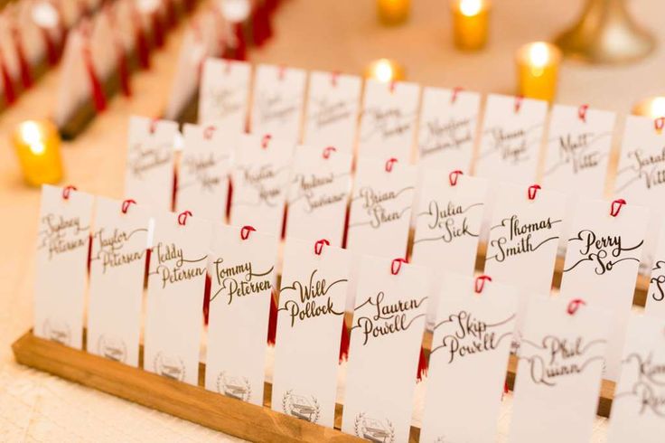 place cards are lined up on a wooden stand in front of candles and other decorations