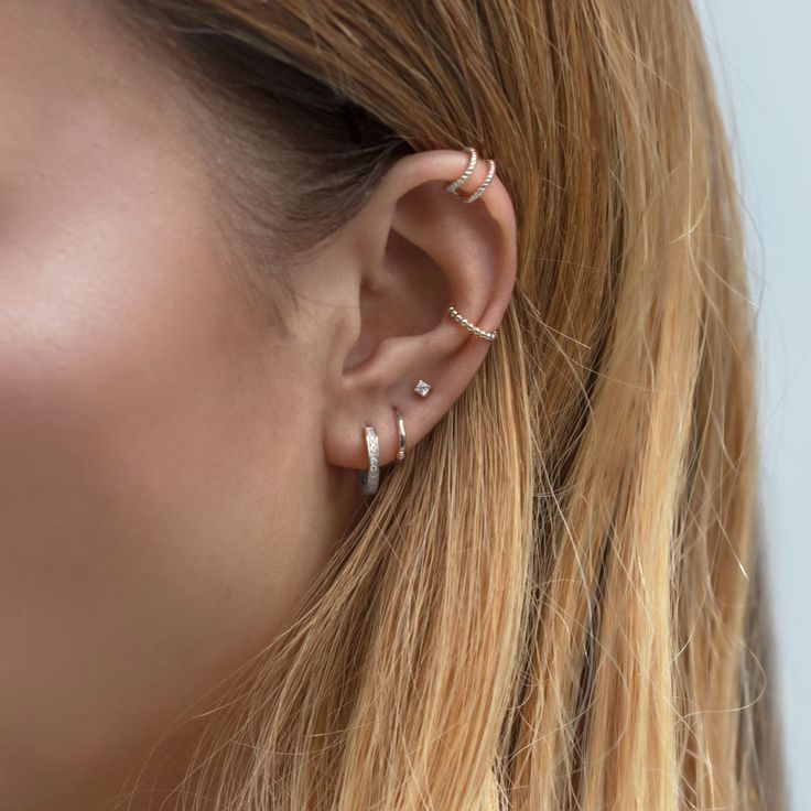 a woman wearing gold ear cuffs with two small hoops on the end of her ear