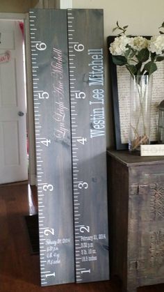 two tall wooden rulers sitting on top of a table next to a vase with flowers