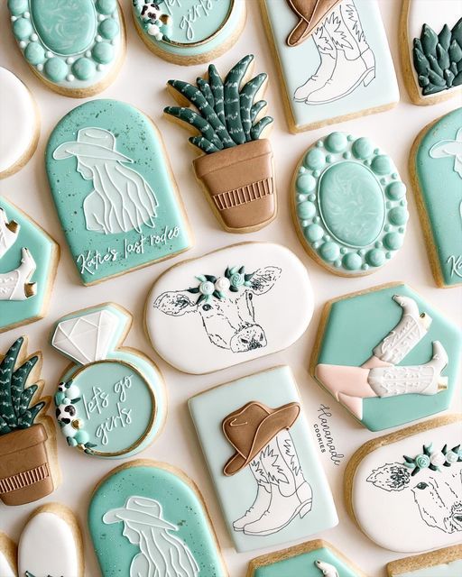 many decorated cookies are arranged in rows on a white surface with plants and potted cacti