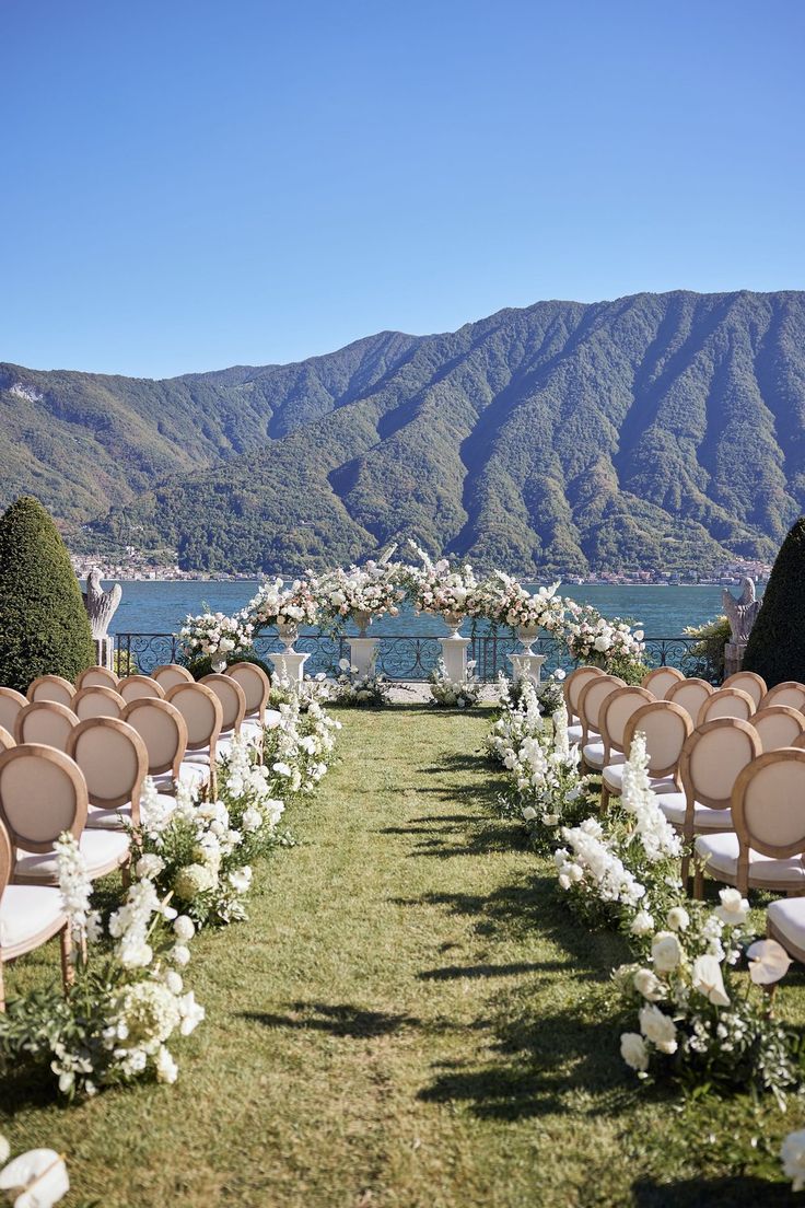 an outdoor ceremony setup with white flowers and greenery on the lawn, overlooking mountains