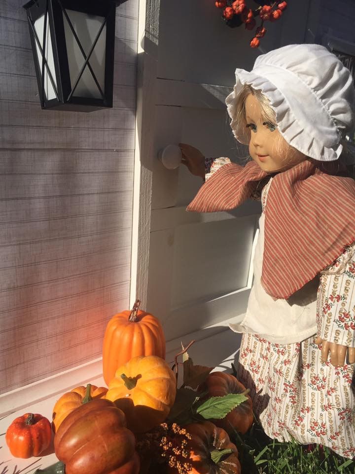 a doll standing next to a pile of pumpkins