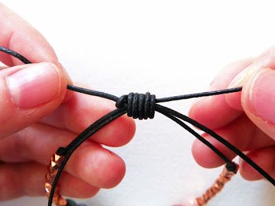 two hands are holding a string together to make a bracelet with beads and leather cord